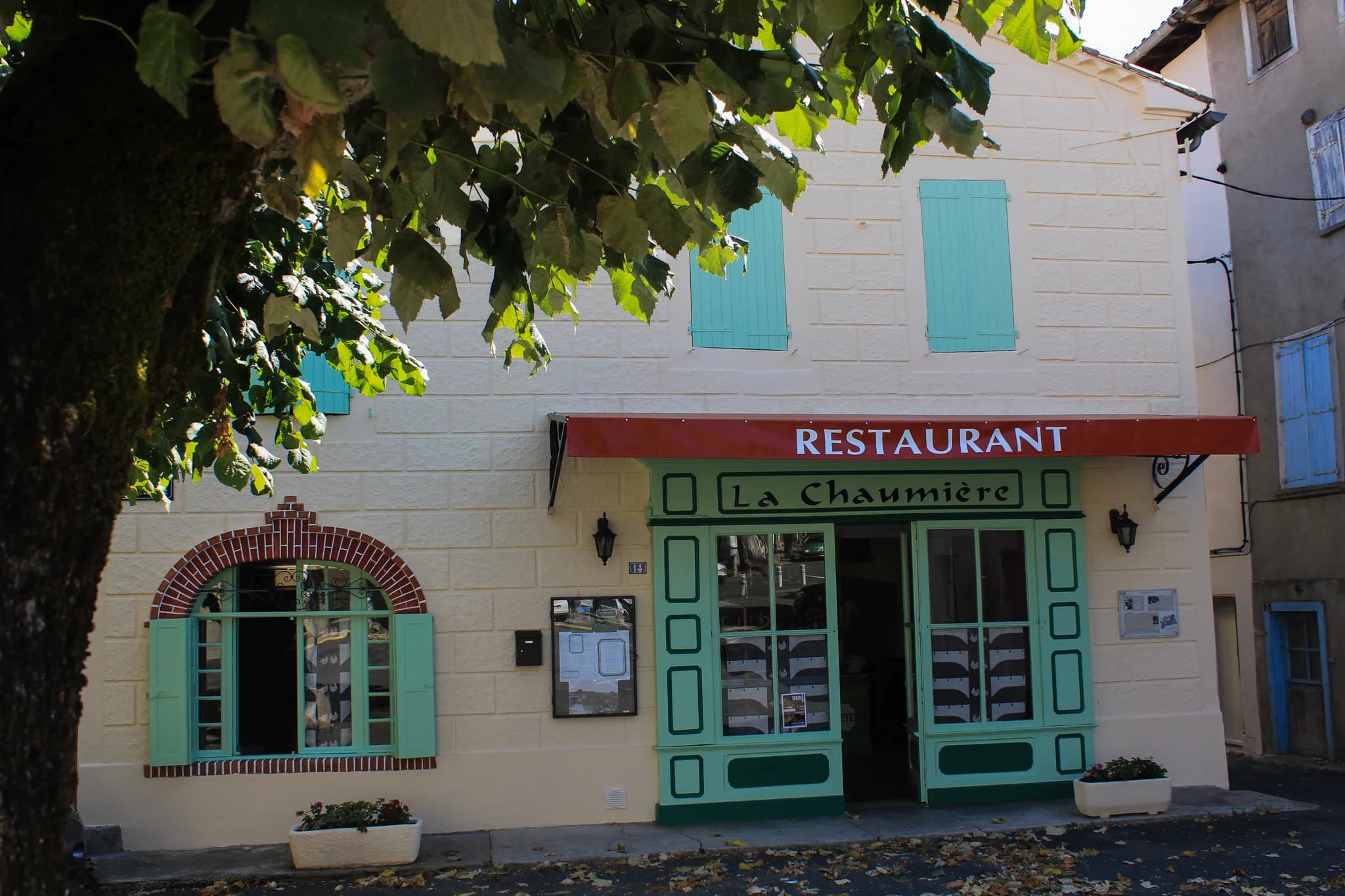 Façade complète du restaurant La Chaumière avec ses volets turquoise et auvent rouge