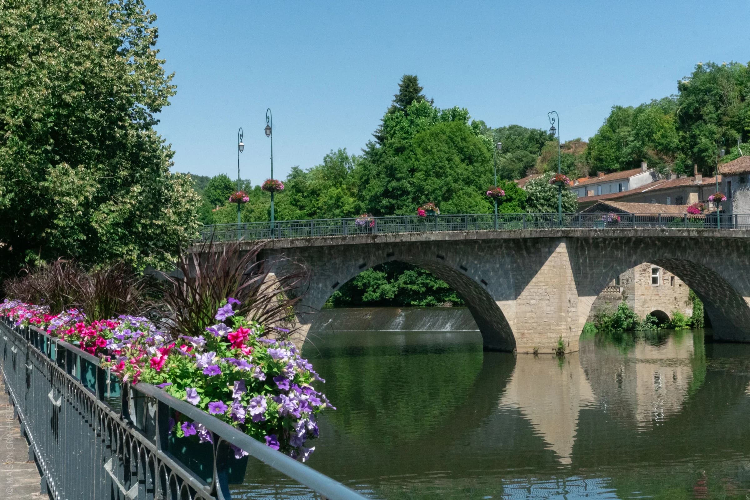 Vue du village de Roquecourbe avec son pont en pierre, la rivière et les fleurs